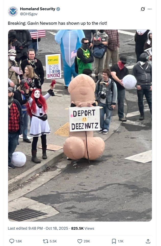 A person in a penis costume with a sign reading "Deport Deez Nutz"