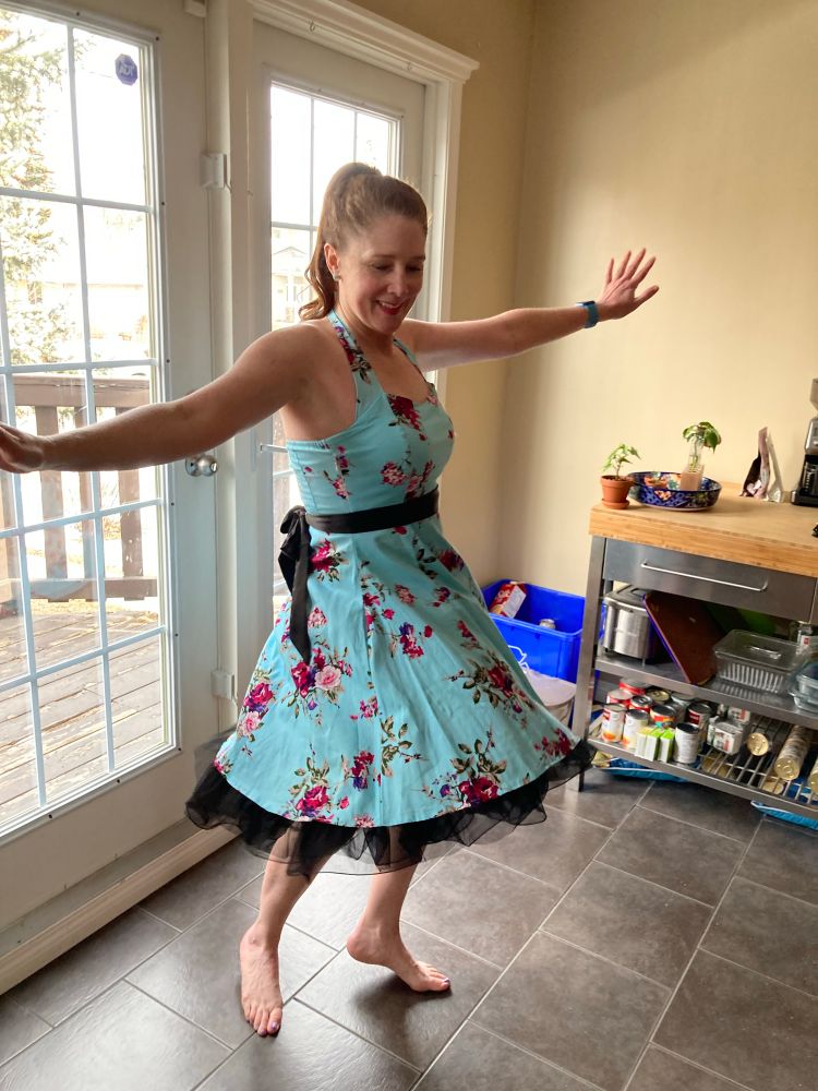 Women twirls whimsically in flowered aqua halter dress, 2023