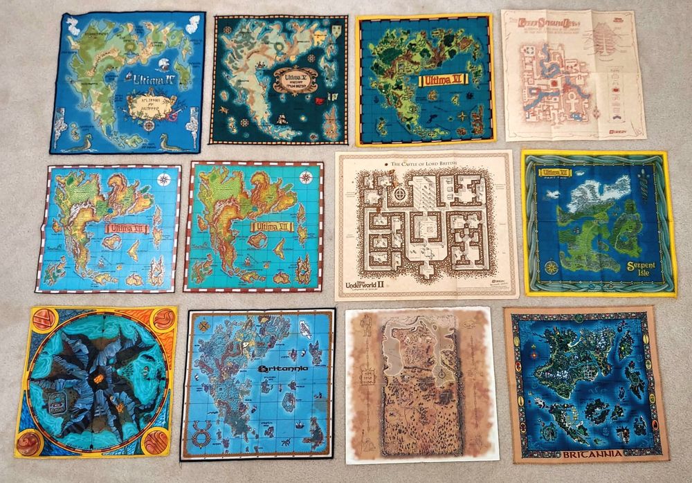A collection of cloth and paper maps from the Ultima series, ranging from Ultima IV to Ultima IX (including Ultima Underworld I and II, and Ultima Online).