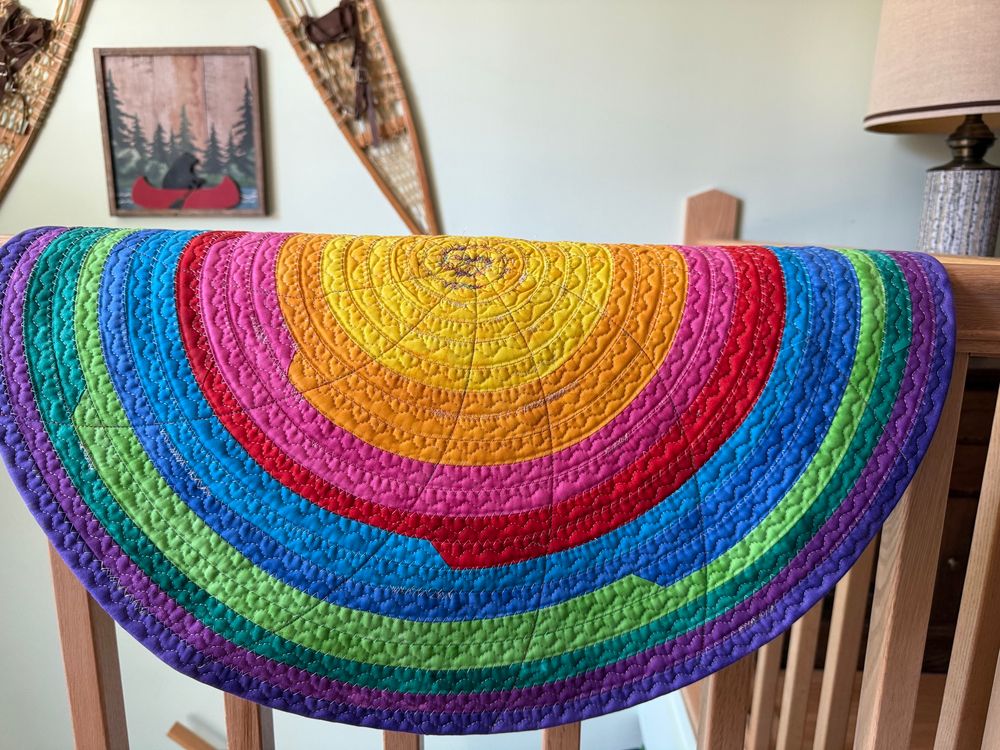 Picture of brightly colored fabric rug hanging on a handrail. 