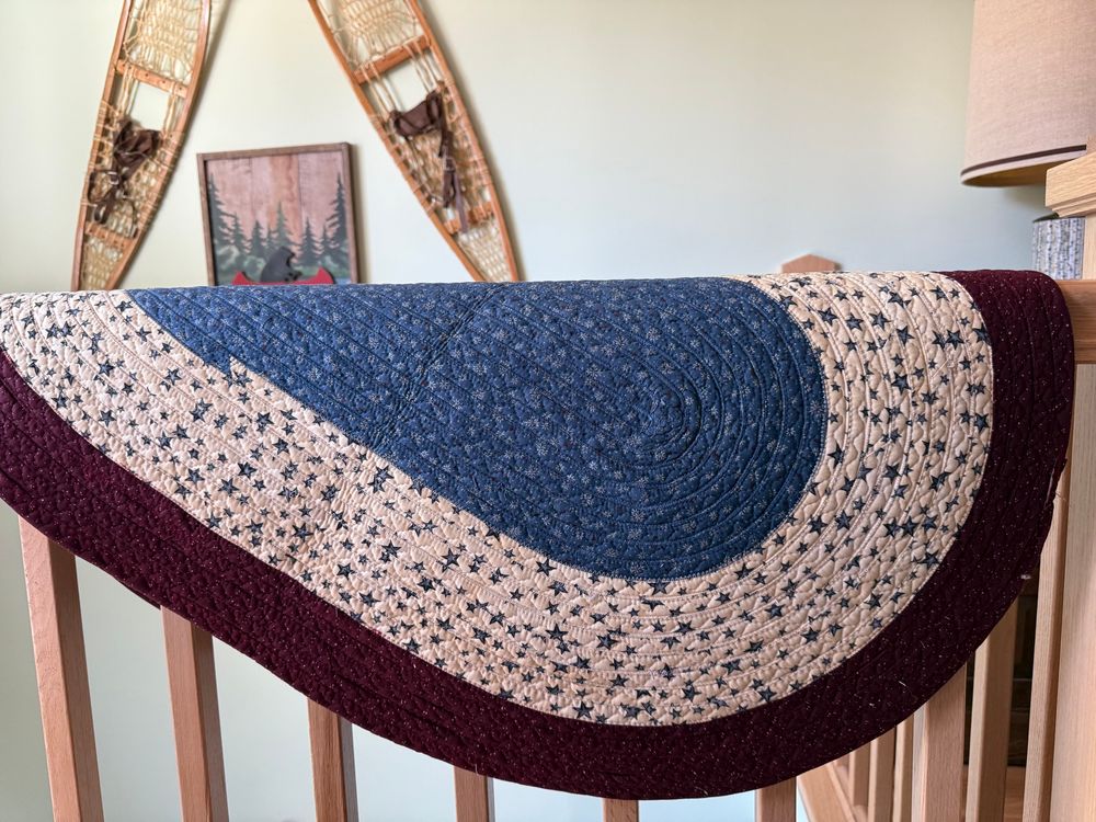 Photo of a red, white and blue fabric rug hanging on a handrail. 