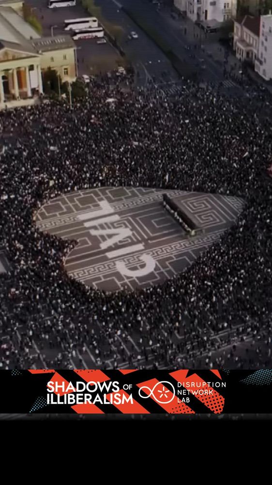 Aerial view of a massive protest in Tbilisi, Georgia, where thousands of people form the shape of a heart around the word “CIVIL” painted on the ground. At the center stands a small stage or platform. The image includes the “Shadows of Illiberalism” and “Disruption Network Lab” banners at the bottom.

