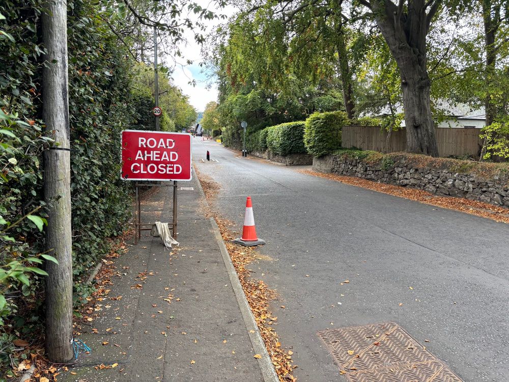 “Road ahead closed” sign blocking the only pavement on a street. 