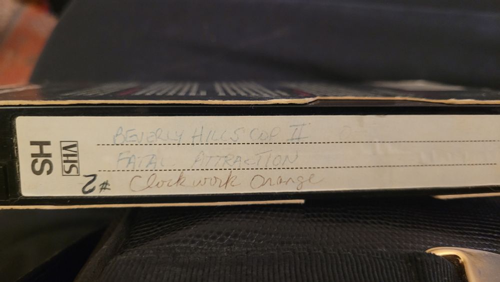 A VHS with Beverly Hills Cop II, Fatal Attraction, and A Clockwork Orange.