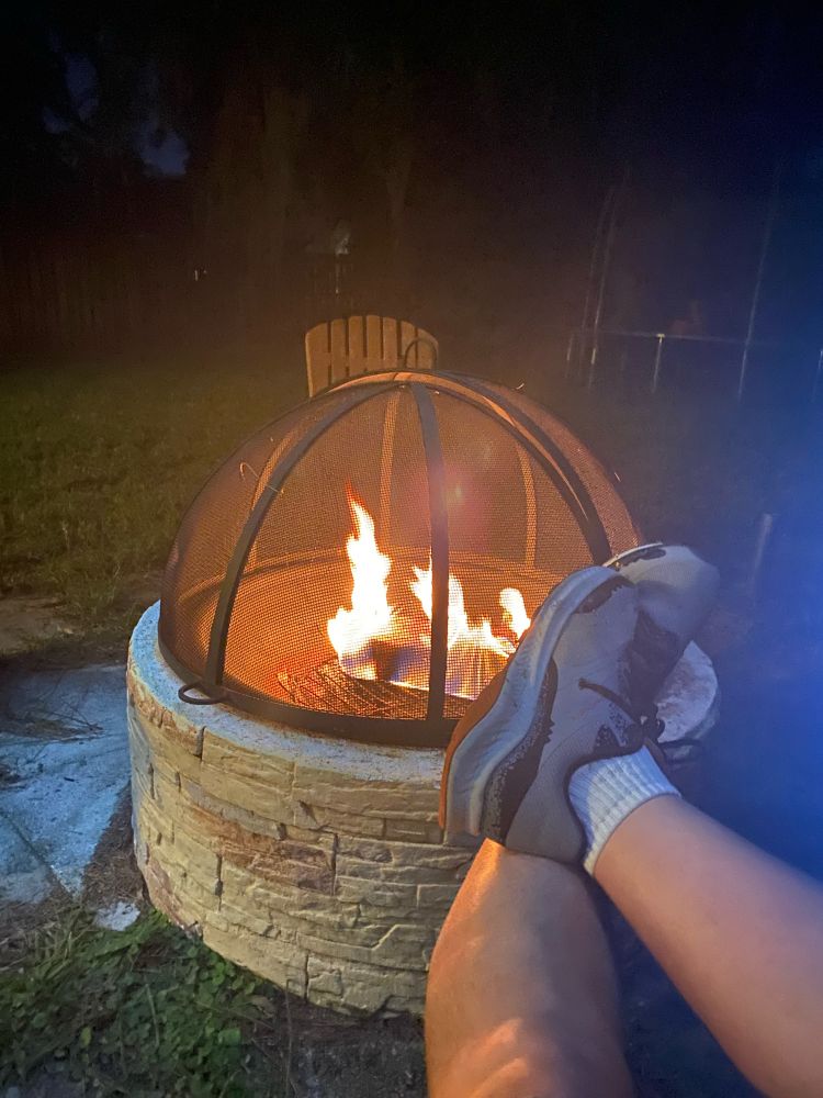 Feet up on a fire put with log burning in the background 