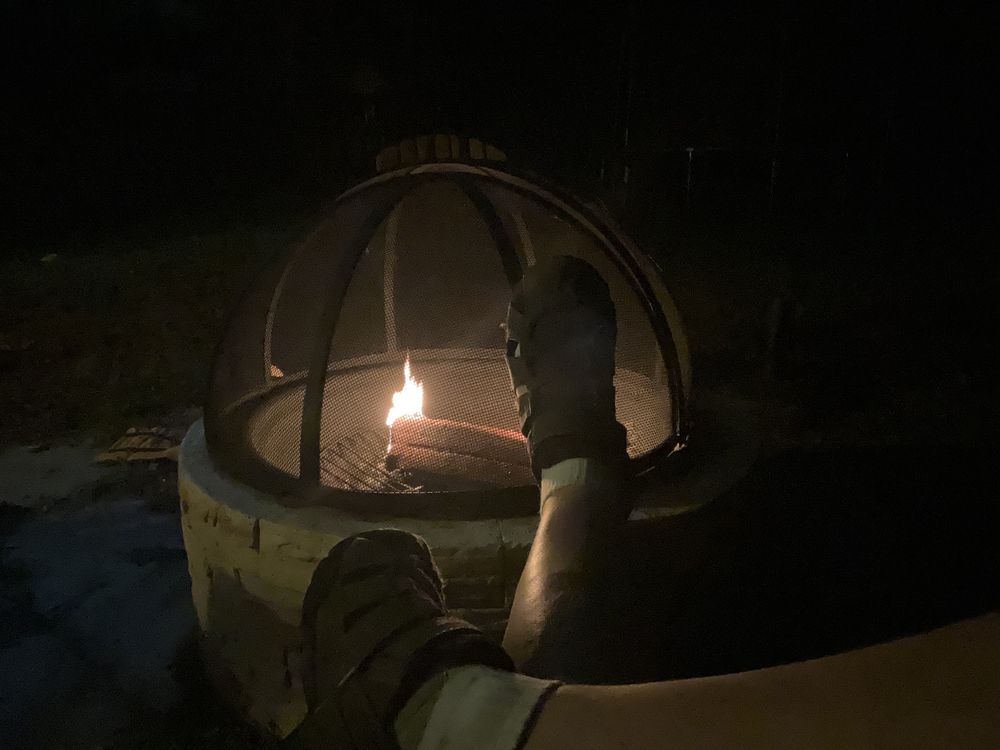 Feet up on a small fire pit with a fire starting. 