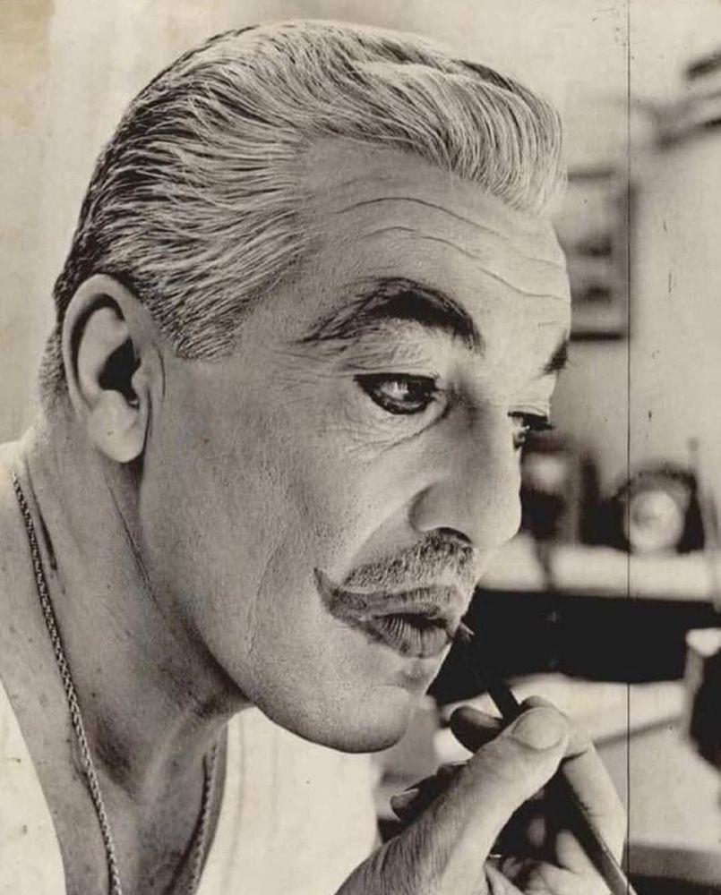 Cesar Romero applies the Joker makeup to his face, white foundation, heavy dark eyeliner and exaggerated smiling lips. He's into it.