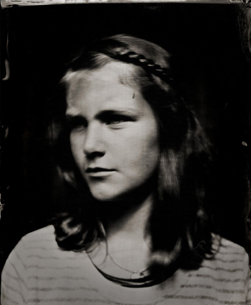  A wet plate portrait of a girl - you can see her head and shoulders - her head is turned to the left ad she has a braid in her hair.