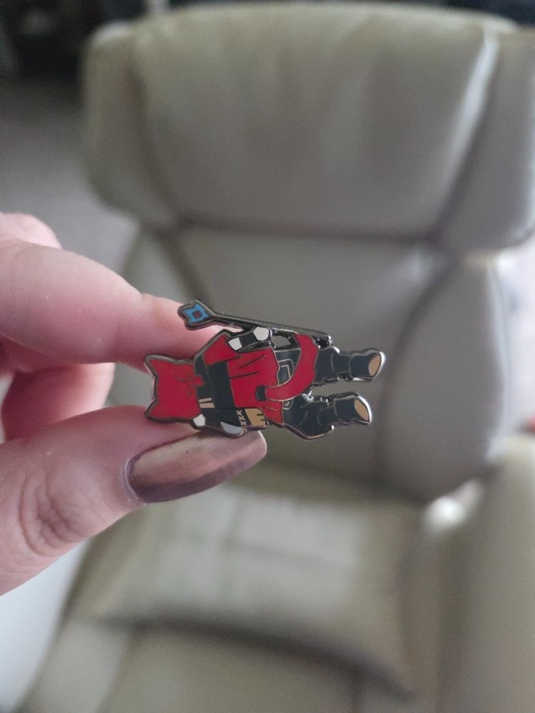 An enamel pin of G'raha Tia out cold.