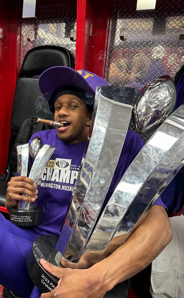Michael Penix Jr. with the Pac-12 Championship trophy and the title game MVP trophy