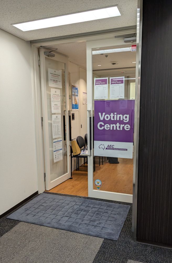 Photo of a door at the Australian Consulate-General that has a purple AEC "Voting Centre" sign in the window.