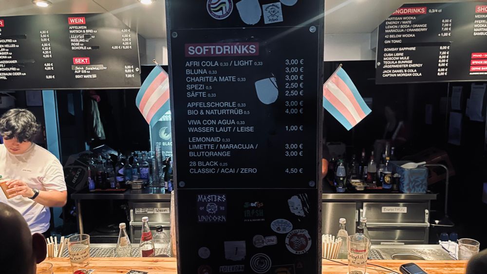 Bar staff had decorated their work area with multiple little trans flags.