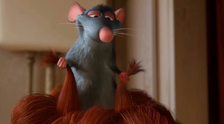Remy, the rat from Ratatouille, standing on Linguini’s head and tugging on two tufts of his hair