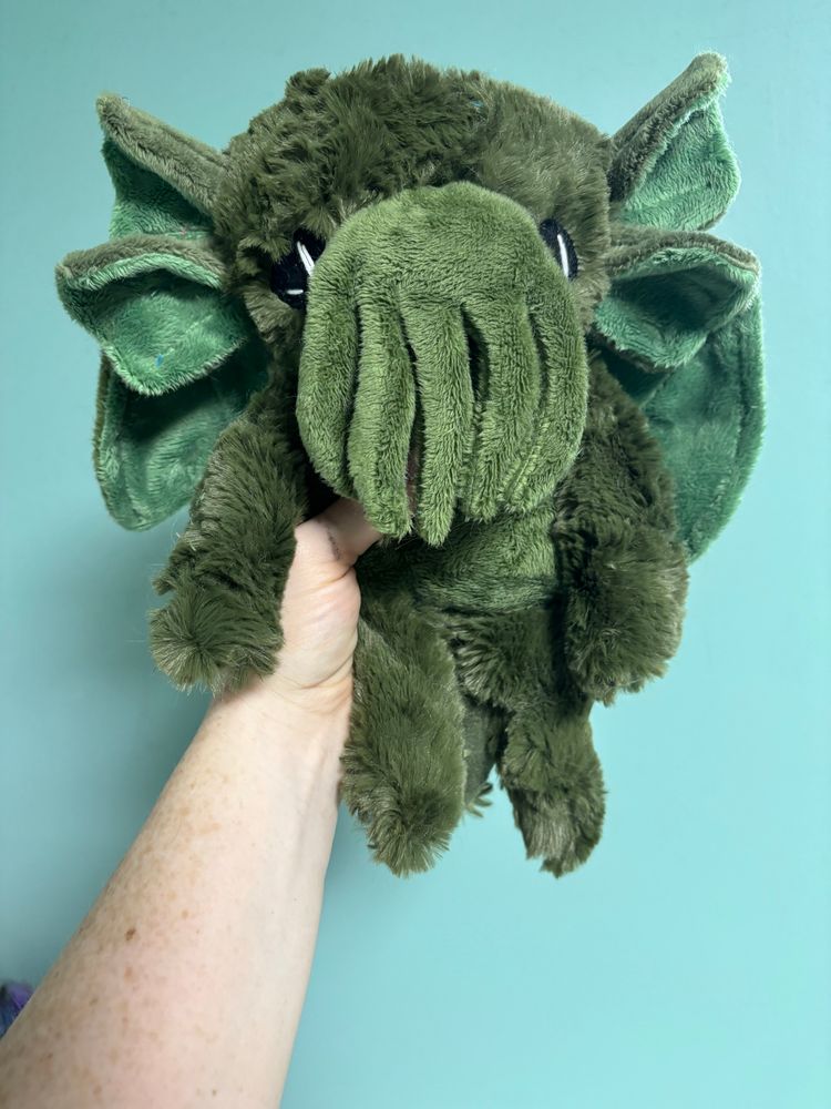 Photo of a hand holding a tiny 7 inch Cthulhu in shades of olive green 