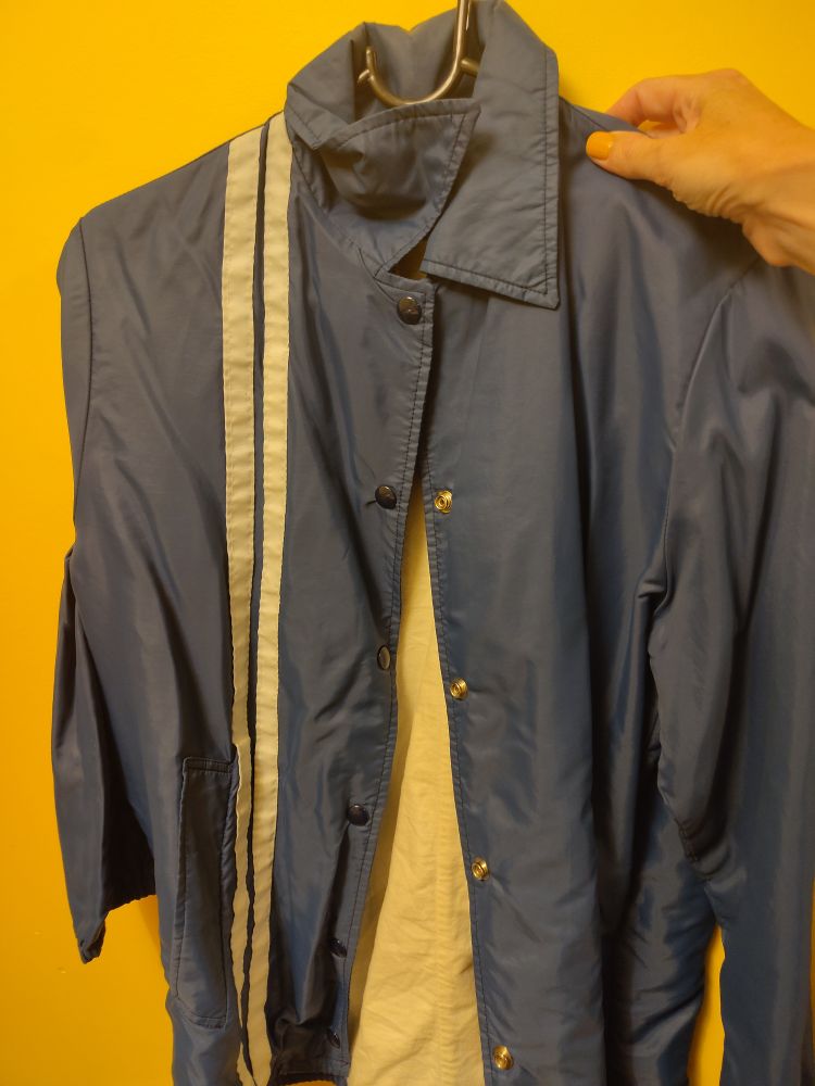 Photo of a blue jacket with two white stripes down one side.