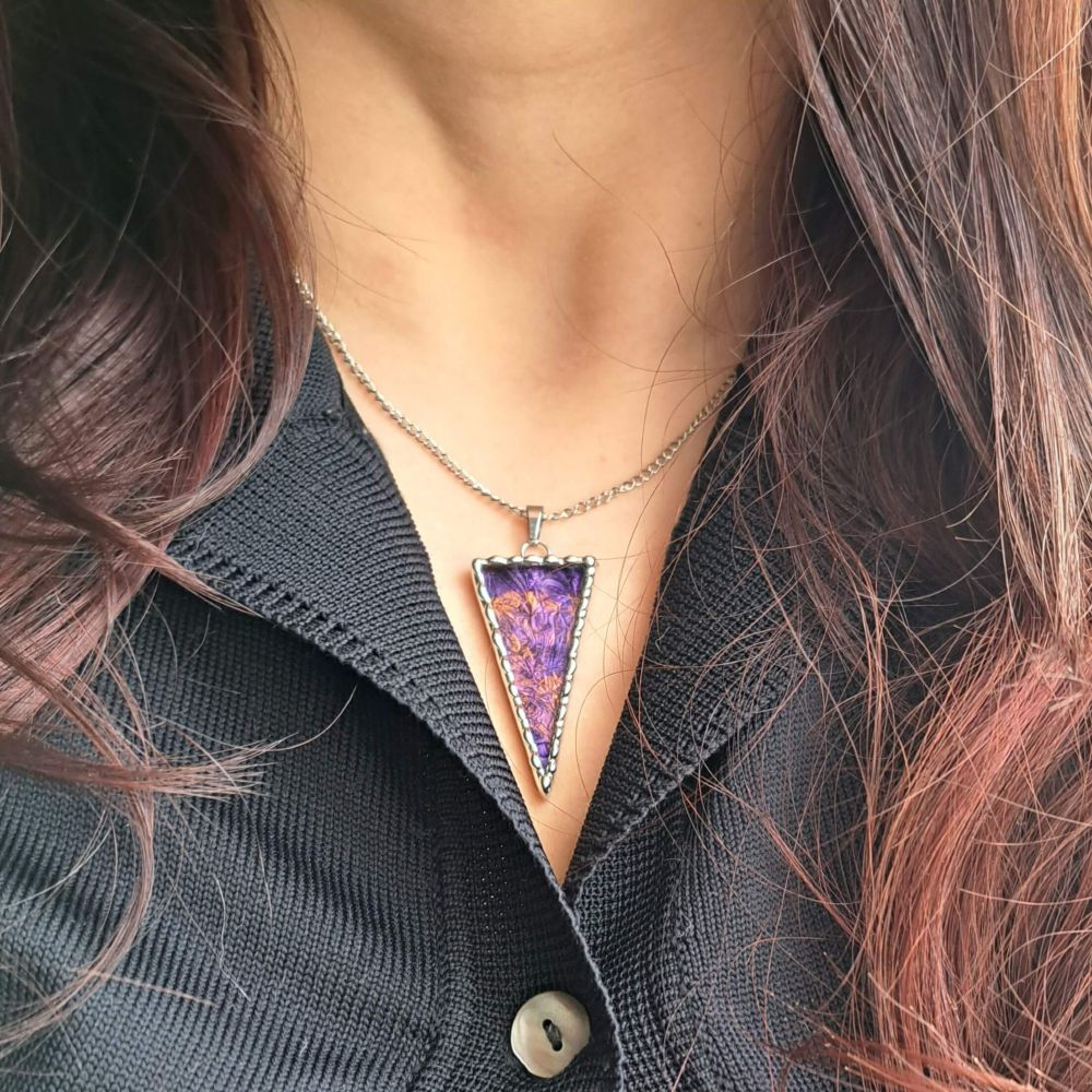 Pendentif de forme triangulaire que je porte au cou. Il est composé de verre miroir coloré (dans les tons violet/bronze) et encadré d’étain pur selon la méthode du vitrail tiffany.
