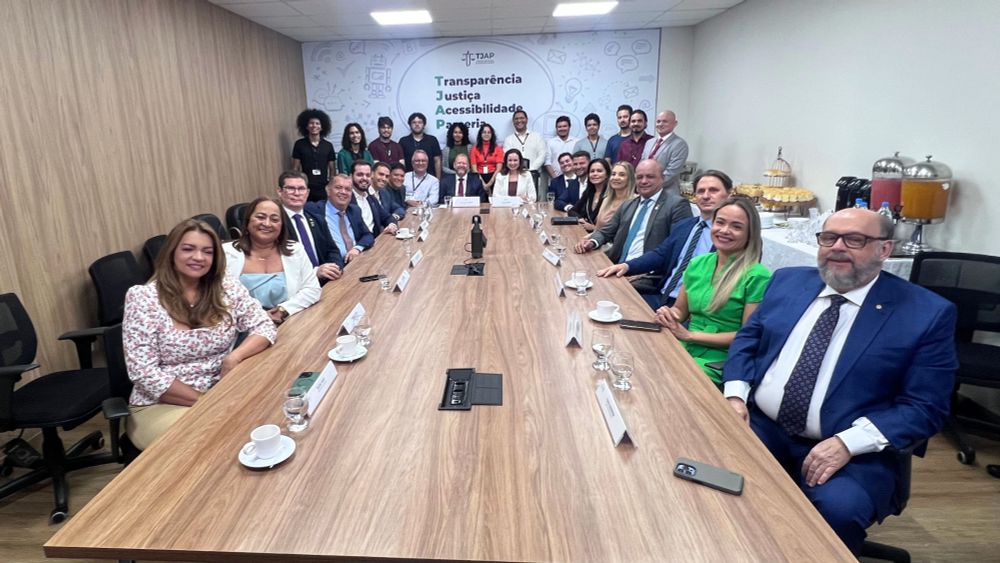 Imagem mostra a sala de reuniões com diversas pessoas sentadas à mesa e, ao fundo, pessoas em pé. Ao fundo, no centro, o presidente do TJAP, desembargador Jayme Ferreira, ladeado de secretários do TJAP, colaboradores e deputados.