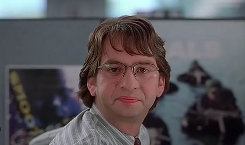 a screenshot from the 1999 movie Office Space depicting an office worker character named Michael Bolton making a dissatisfied face