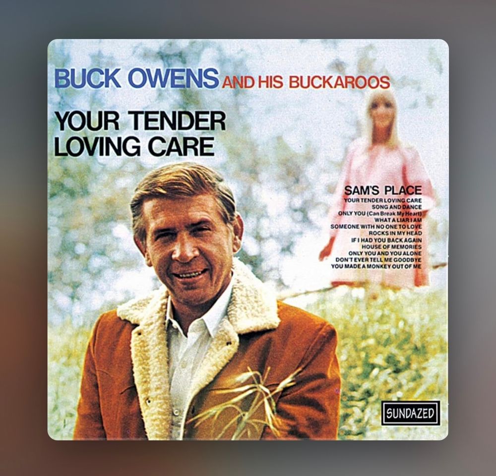 Album cover to Buck Owens’ “Your Tender Loving Care”: Buck in burnt orange jacket, there’s a let in a pink dress out of focus in the background
