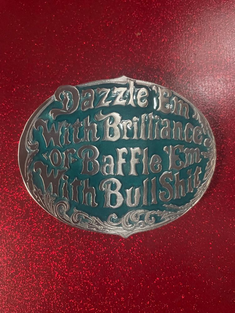 A novelty belt buckle with the W.C. Fields quote “Dazzle ‘Em With Brilliance or Baffle ‘Em With Bullshit” on it, polished silver lettering over a blue background.  People staring at my crotch will be greatly amused, (but for a new, less sad reason)