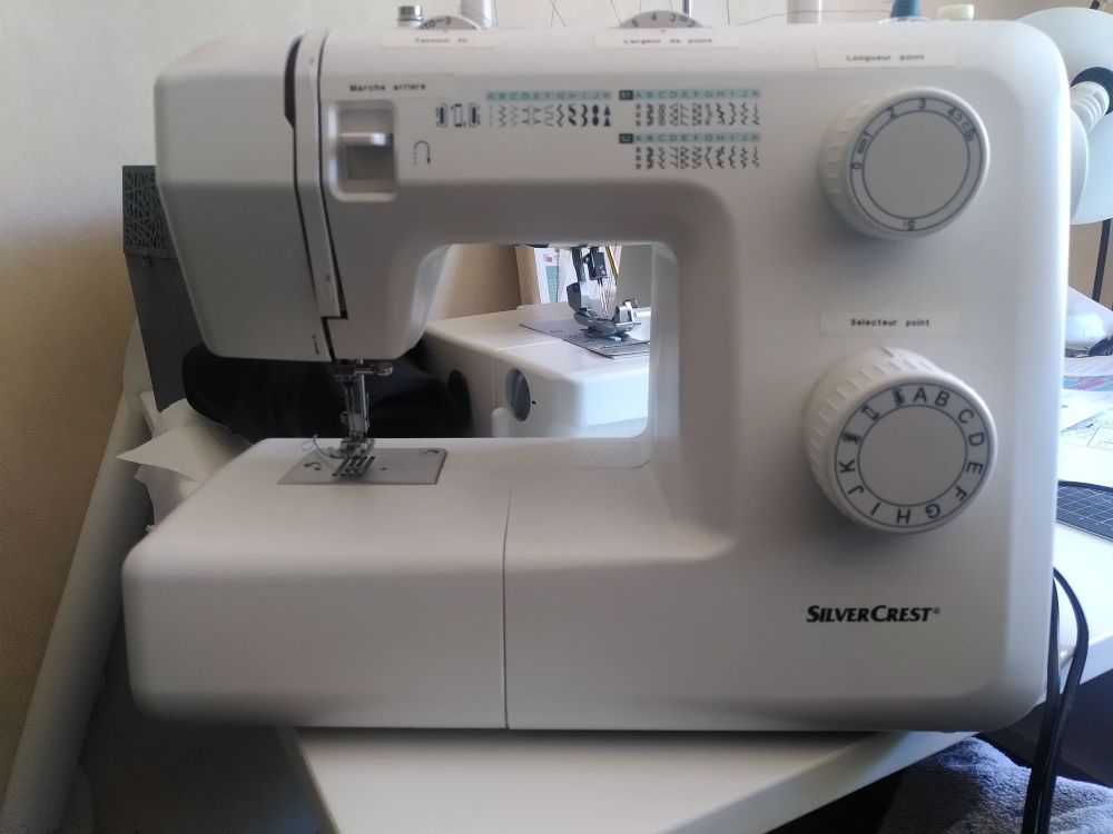 Une machine à coudre silvercrest blanche, avec les inscriptions en bleu clair et bleu foncé.