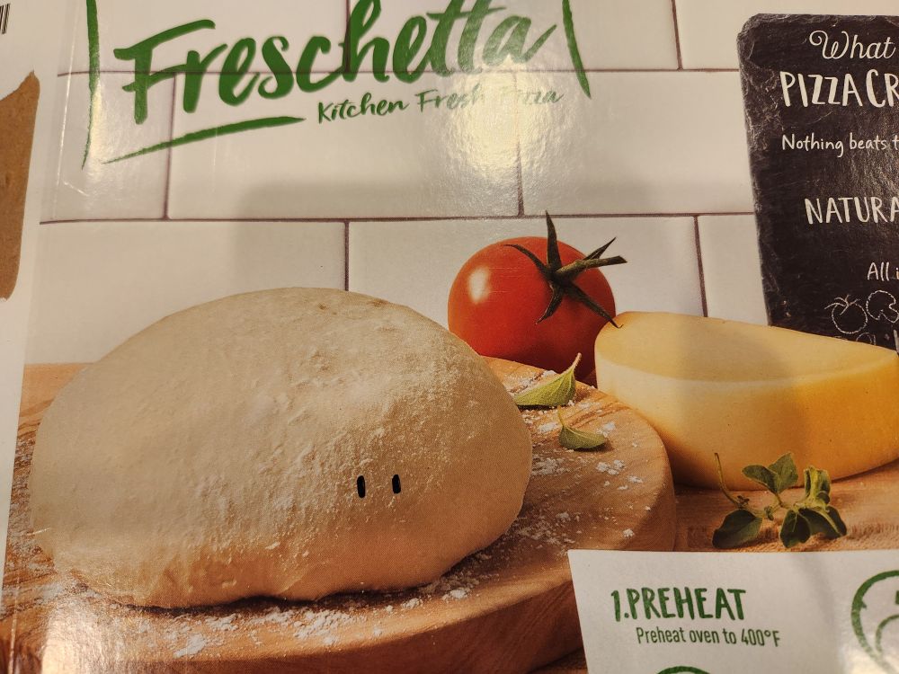 Photo of a blob of pizza dough with two little eyes drawn on.