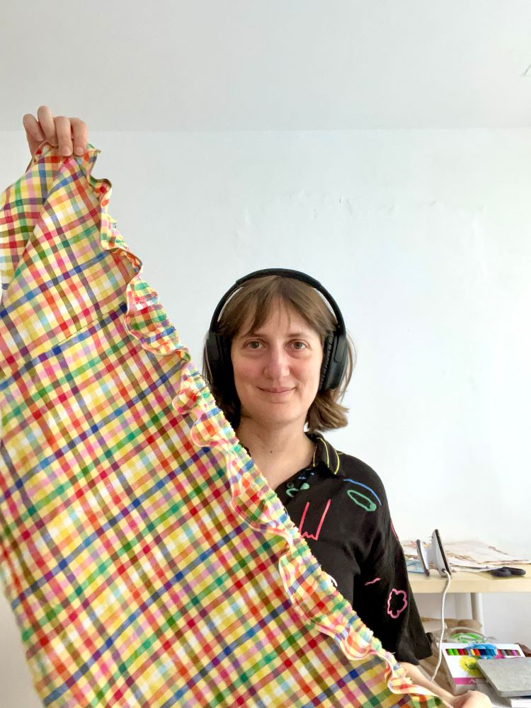 Self portrait photo of me holding a fabric to which I’ve sewed ruffles