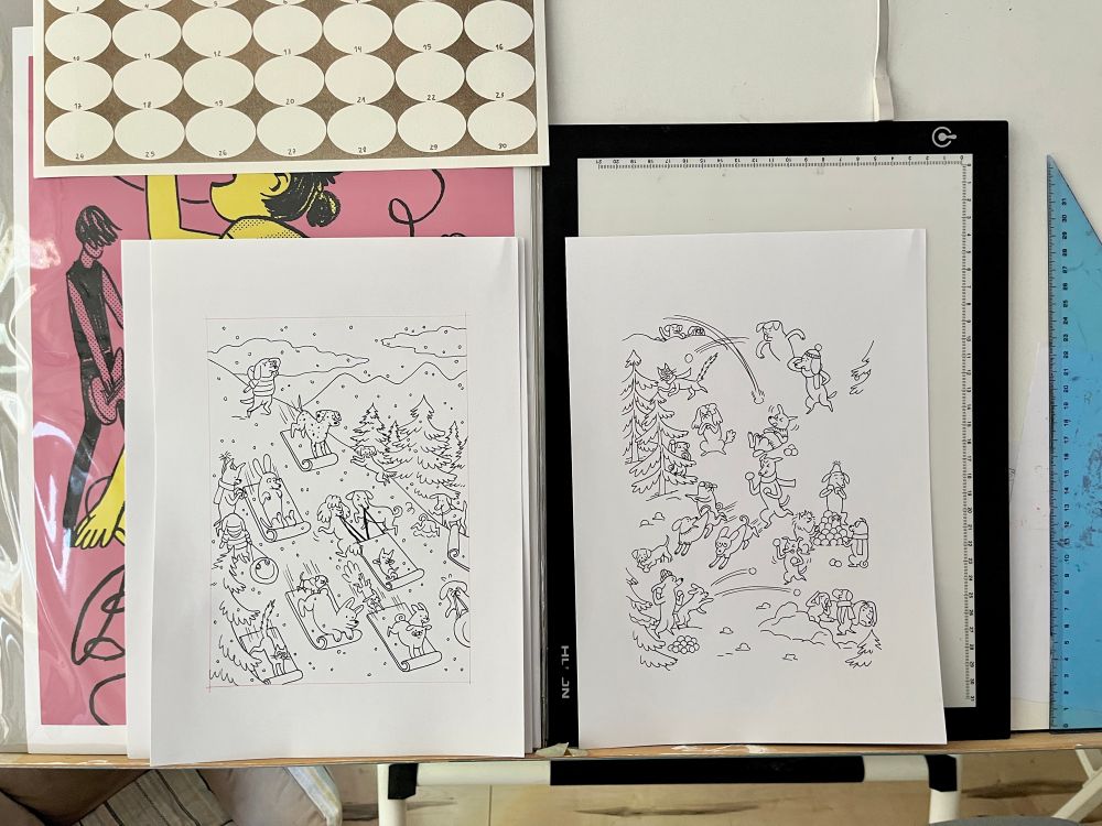 2 Inked illustrations photographed on my table, surrounded by the light table, ruler and some prints