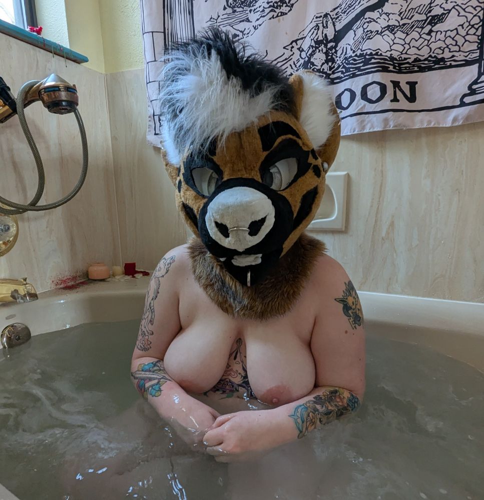 A photo of me in my hyena suit head, I am nude in the bathtub.