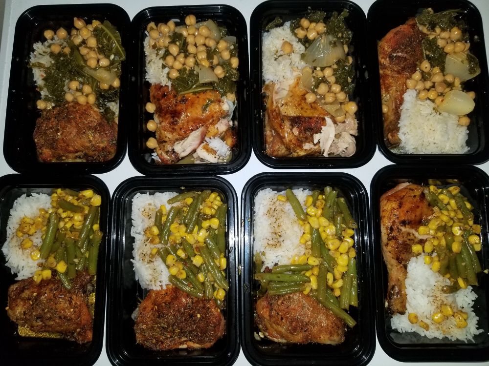 Meal prep containers layed out and filled with kale, chickpeas, garlic, and onions. Bottom is corn, green beans, and garlic. All have rice and baked chicken.