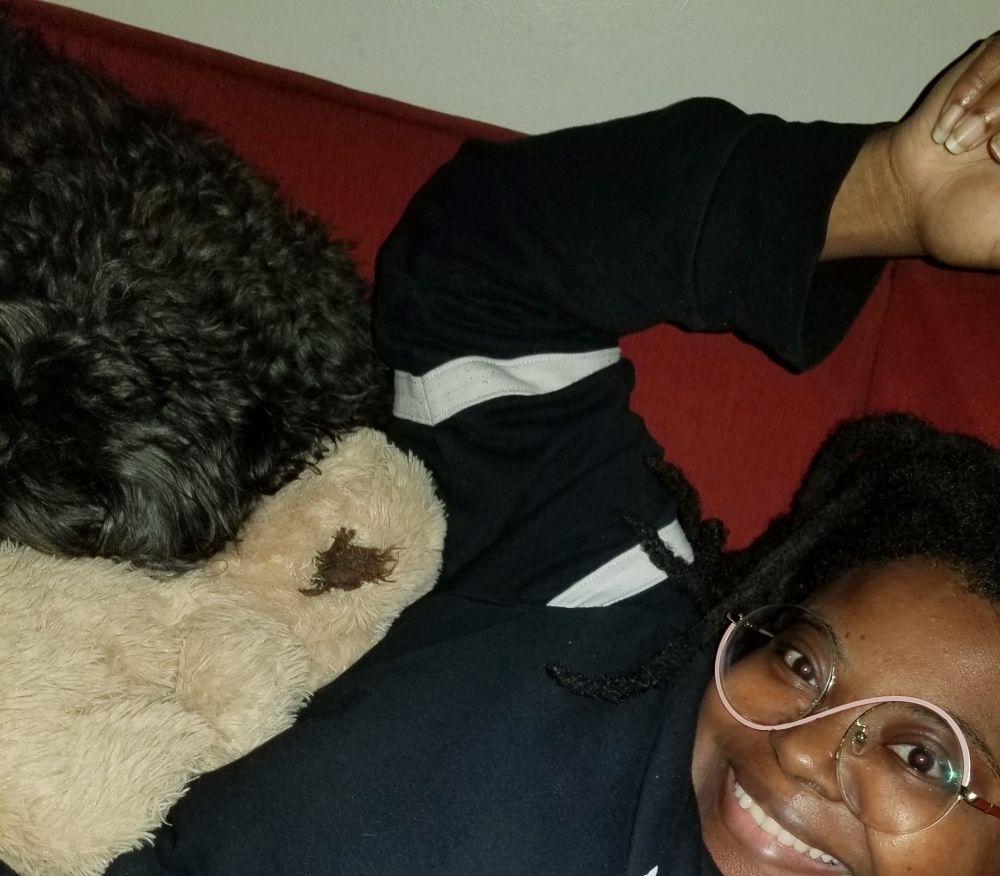 Woman and yorkiepoo dog cuddled.