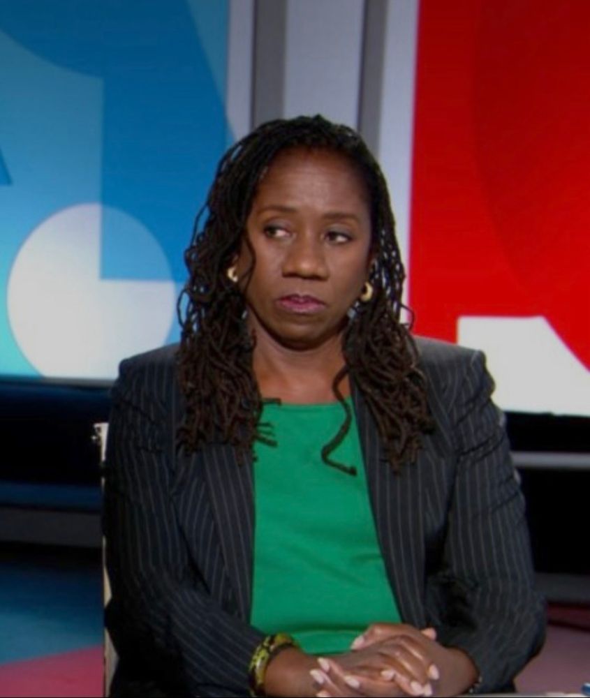 The black lady is wearing a green shirt and blouse giving her white colleague the side eye while he lies.