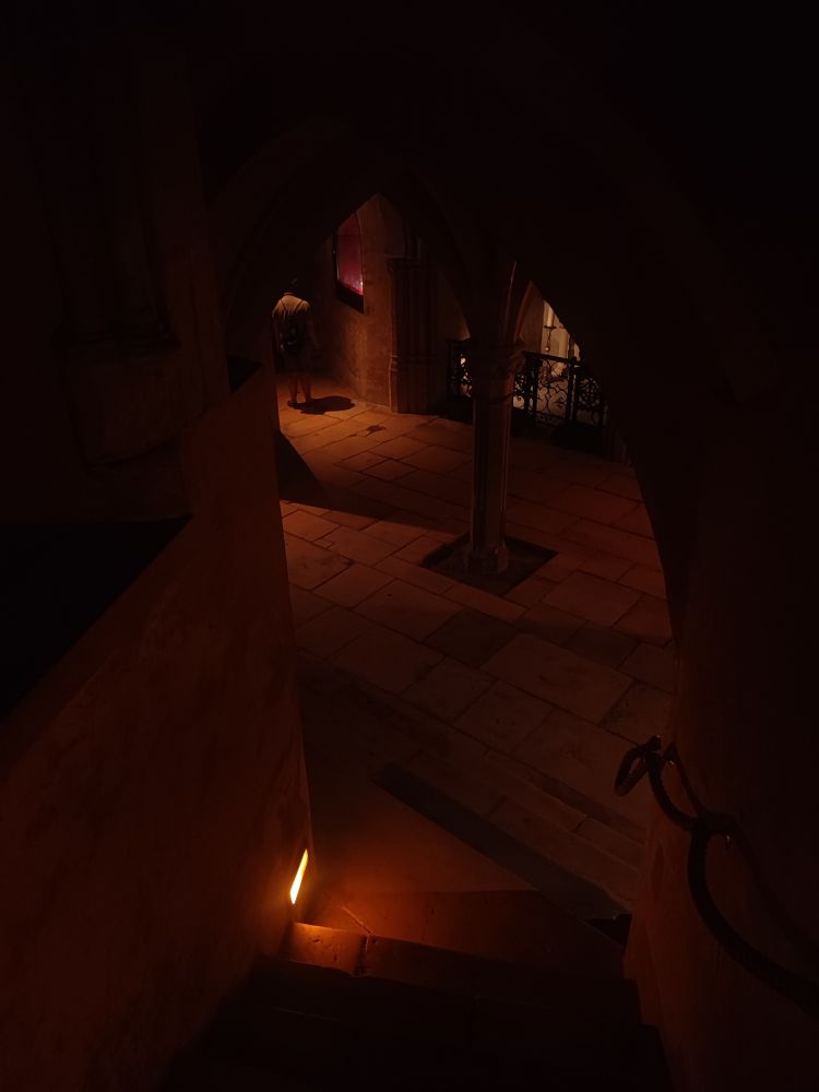 Vue en plongée sur une crypte obscure éclairée d'orangé