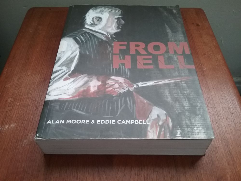 Big thick paperback of From Hell by Alan Moore and Eddie Campbell on a wooden table.