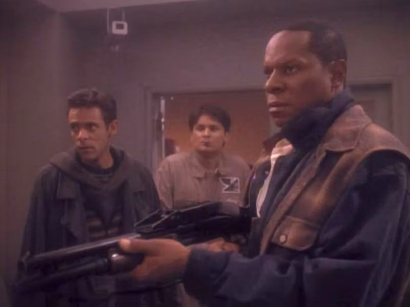 Screenshot from Star Trek: Deep Space Nine 'Past Tense' showing Benjamin Sisko in 2020s civilian clothing brandishing a shotgun.