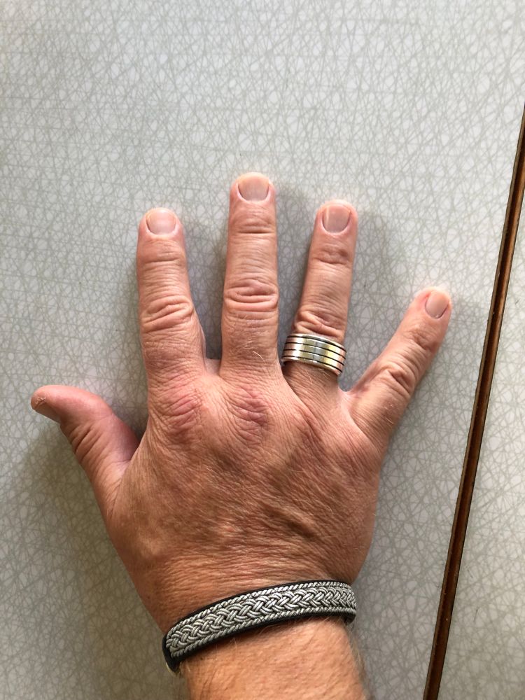 Min högerhand med bred silverring på ringfingret och armband i läder och tenn. 