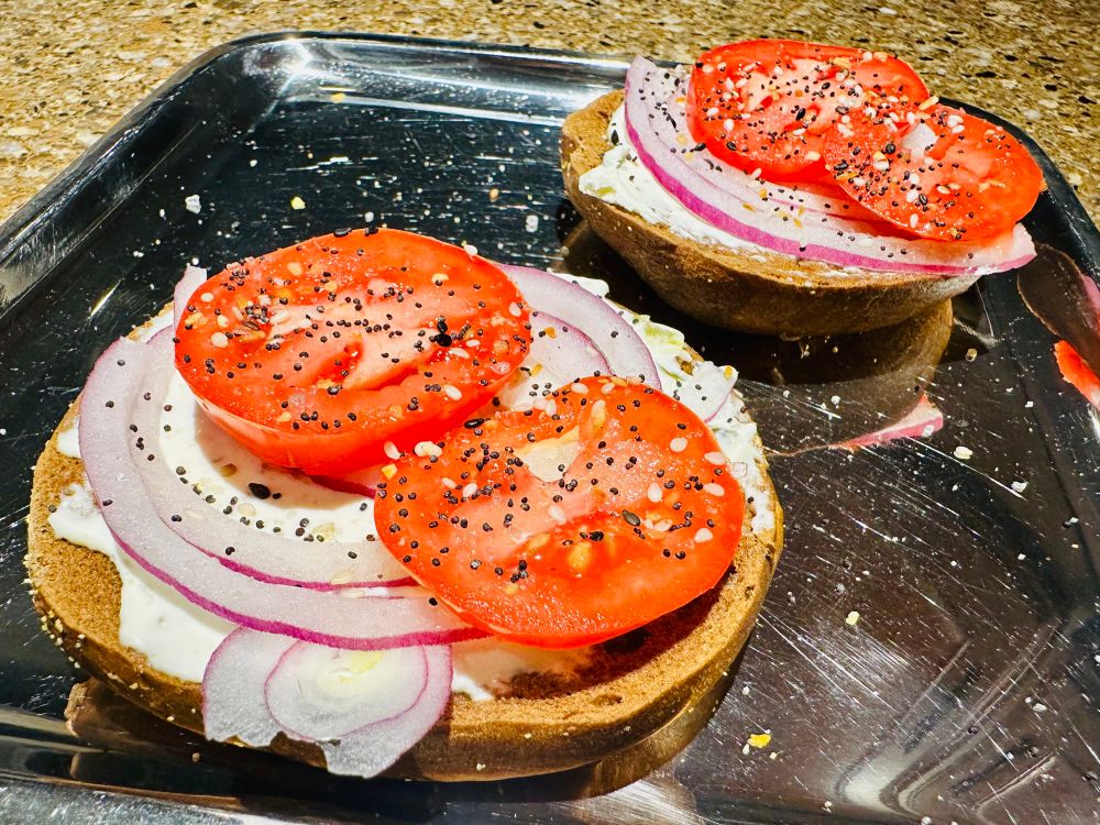 Toasted pumpernickel bagel with cream cheese, onions, and tomato.