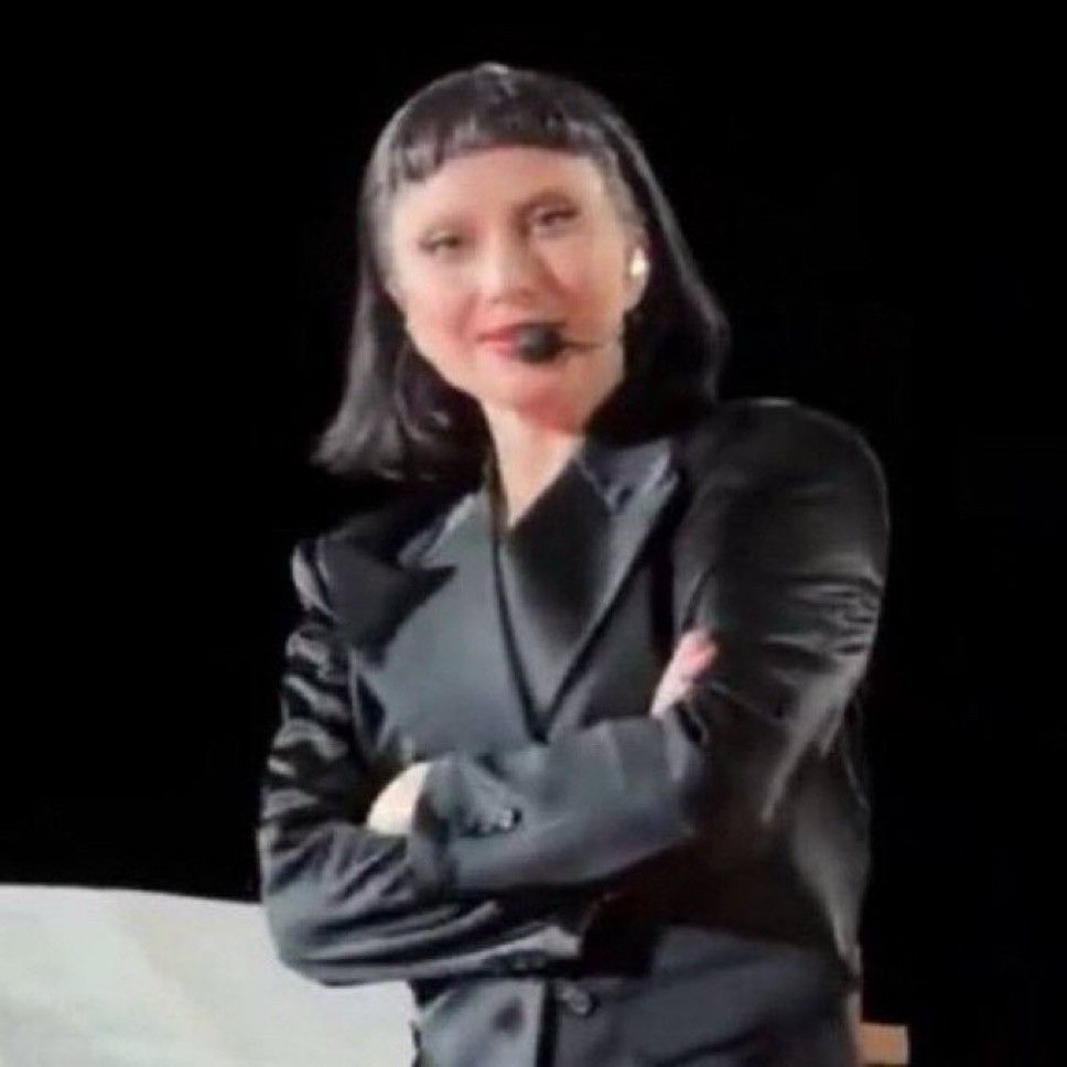 Lady Gaga com uma cara meio engraçada, meio irônica com os braços cruzados olhando pra foto.