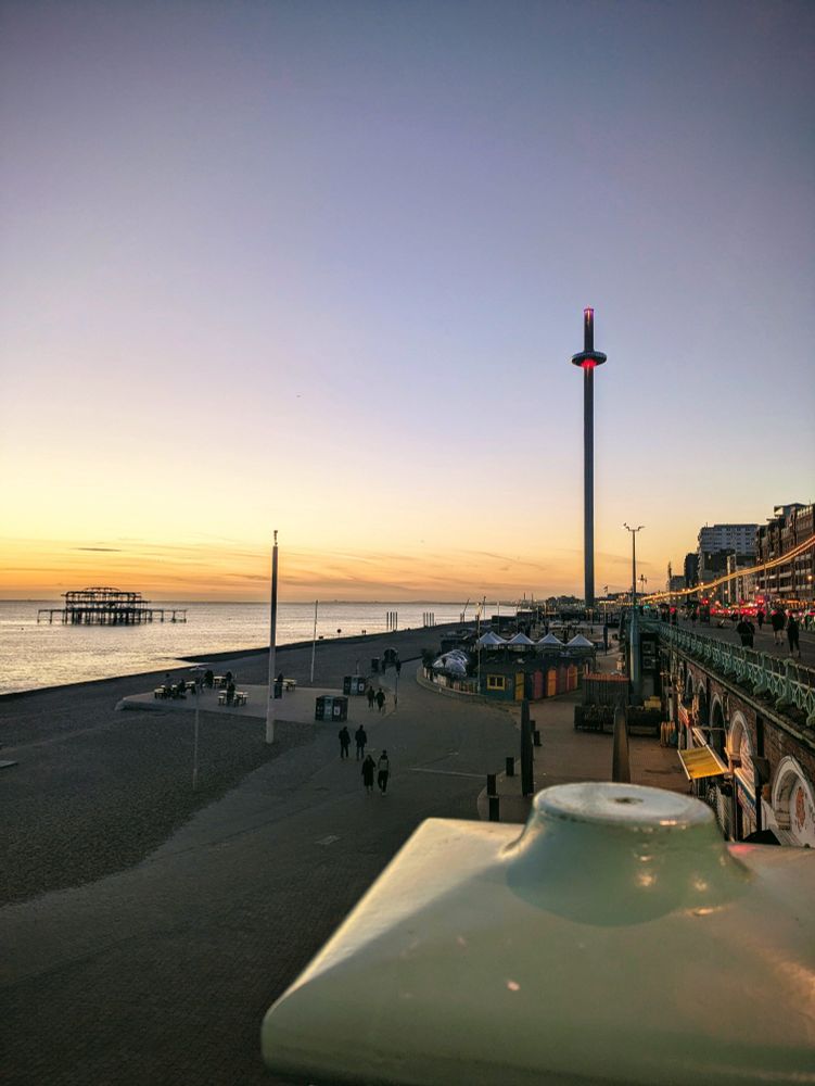 Sunset scene of Brighton beach with i360 and West Pier in background. Hotel lights to side 