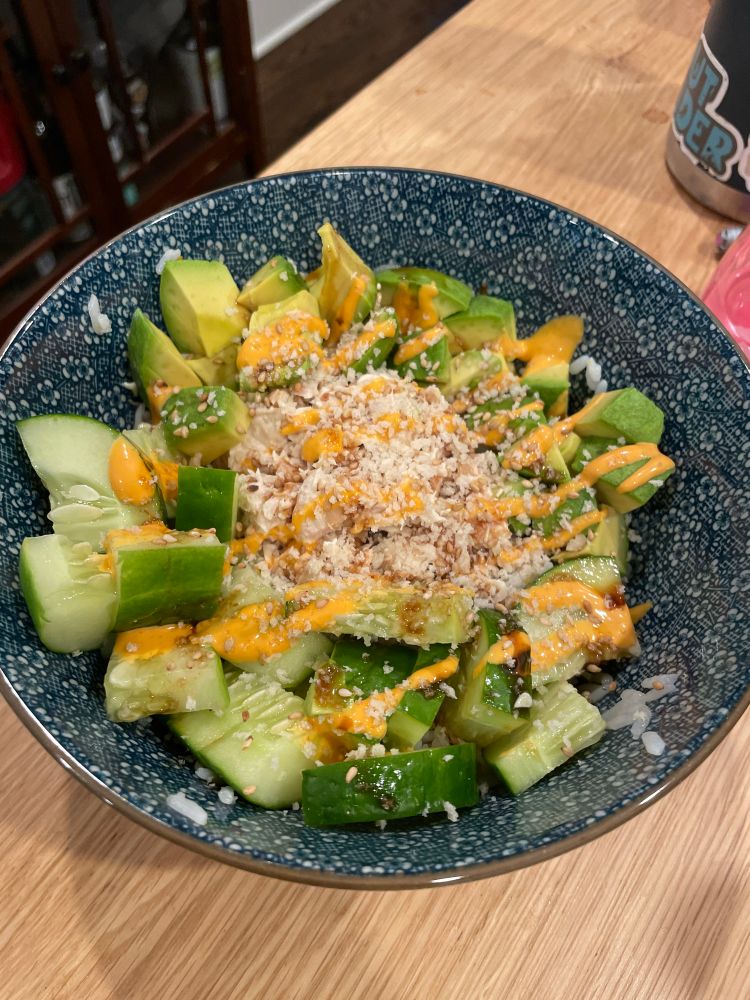 Blue pattern bowl holding a Poké bowl of rice, tuna mayo, avocado, cucumber, Sriracha, mayo, Panko, and Sesame seeds