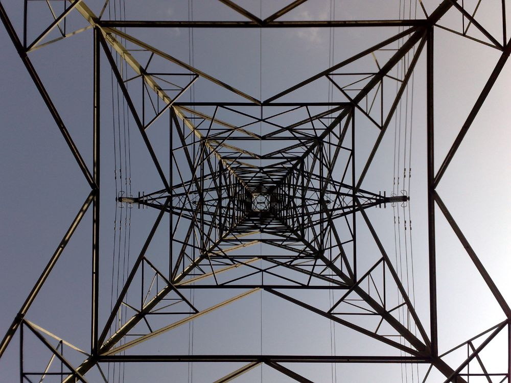 View from the bottom of an electricity pylon looking up to the apex and showing the symmetrical structure of beams and cross braces