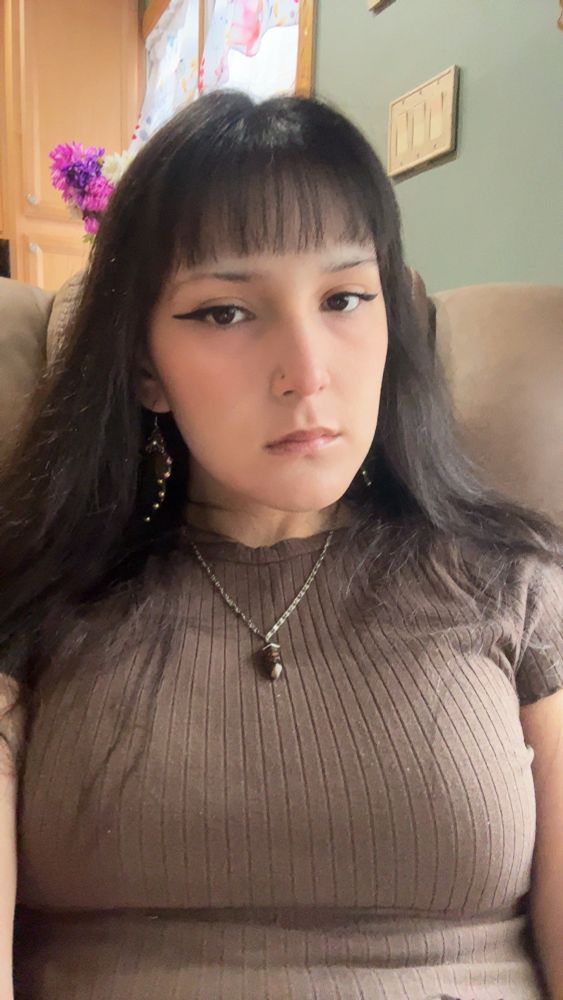 Aria wearing all brown with butterfly wing earrings and a crystal necklace