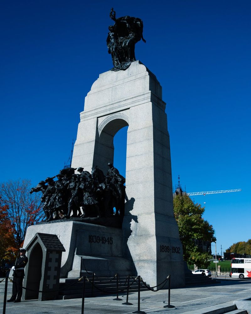 National War Memorial with an OC Transpo bus in a Remembrance Day bus wrap design in the background