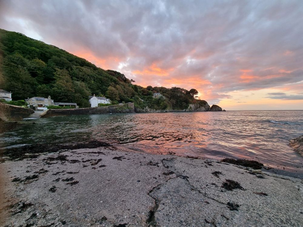 Colourful sky reflected on sea with while houses on a hilled shoreline