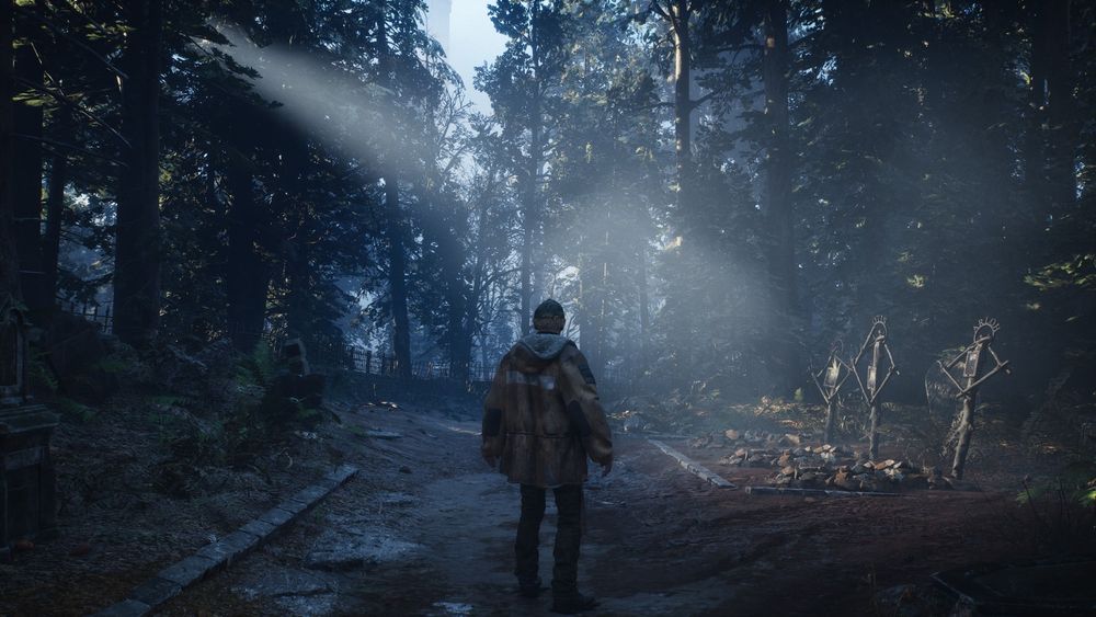 Mann mit Schirmmütze in beigem Parka steht auf matschigem Waldweg. Der Wald ist feucht und dunstig, durch die Baumkronen scheint Sonnenlicht. Zur Rechten drei provisorische Gräber