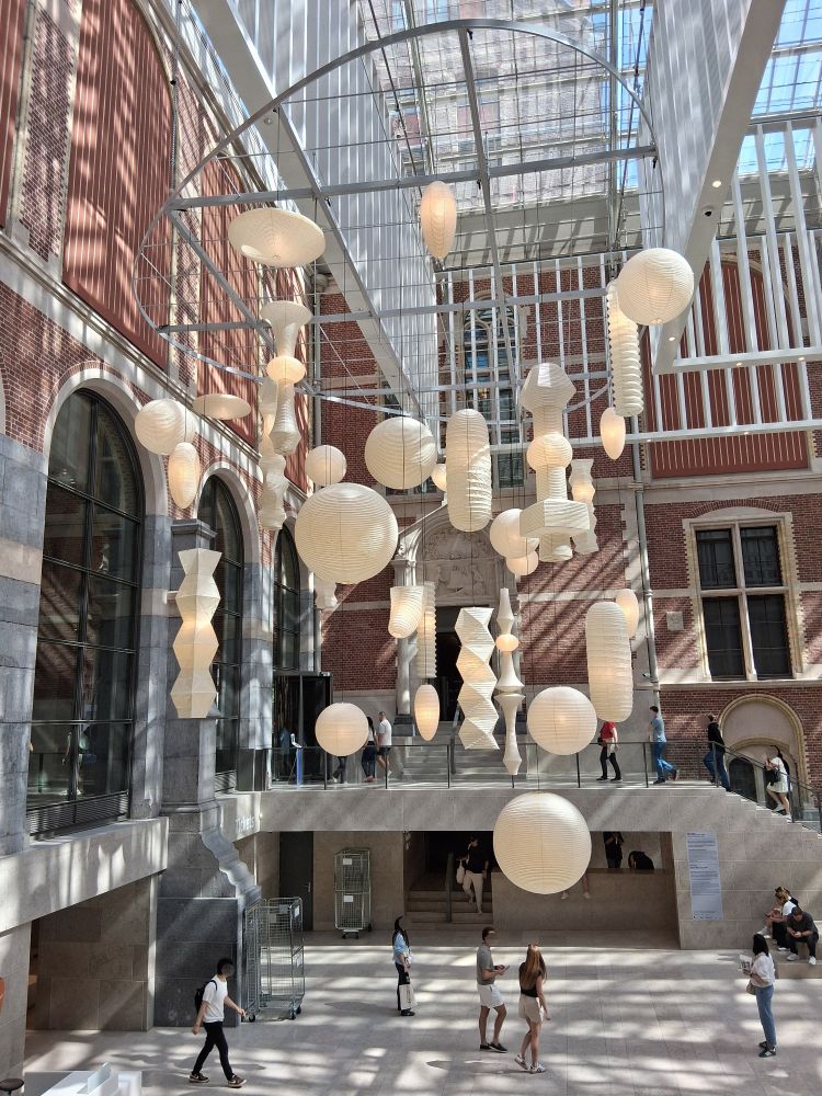 A picture of the artwork "Akari lamps" by the artist Isamu Noguchi (1904 - 1988). The lamps are exhibited at the foyer of Rijksmuseum Amsterdam. Namjoon of BTS has posted a picture of this in the same frame on his Instagram account.

The artwork is described by the museum as follows:

"These lamps are inspired by traditional Japanese lanterns. Noguchi designed them as light sculptures made of washi paper and bamboo. The Japanese word Akari refers both to light in terms of weight and illumination. Since the 1950s, the lamps have been produced in various shapes and sizes - and have since become widely imitated design classics." 
