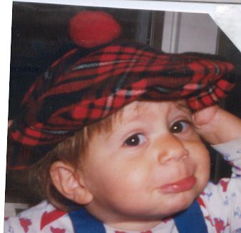 Me as a toddler pulling a face and wearing a tartan bonnet