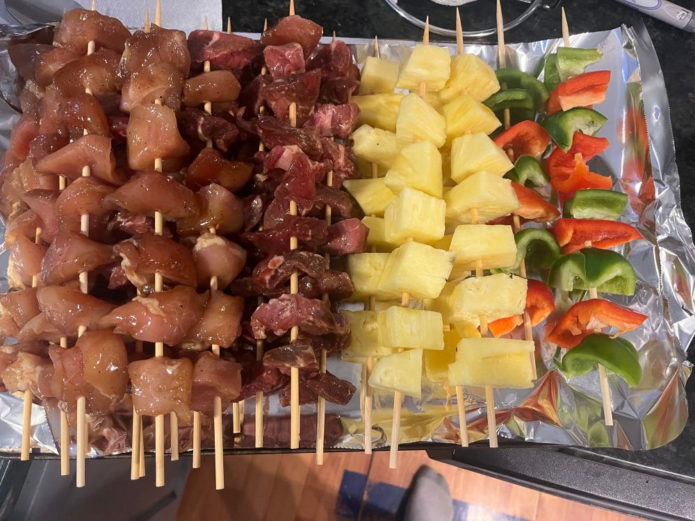 Picture of everything on skewers , steak, chickens, pineapple, red and green peppers ready to grill