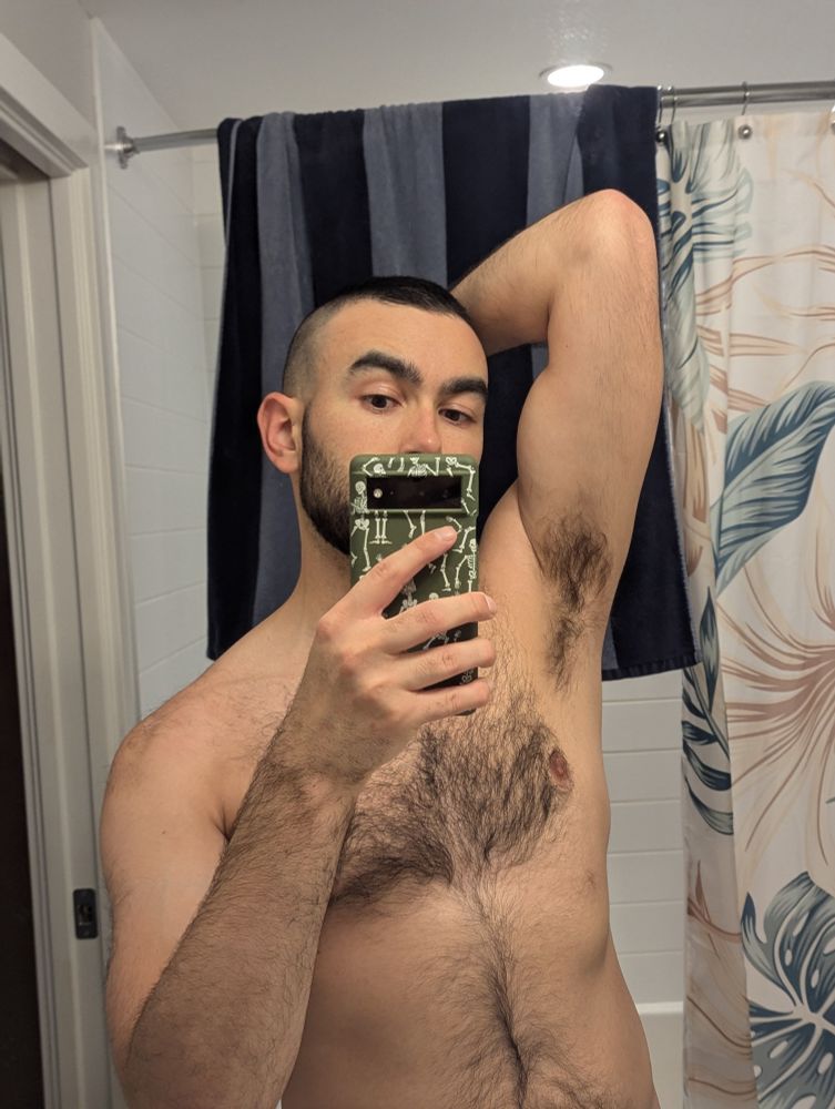 Hairy person taking a mirror selfie with their elbow up to show off their hairy pit and maybe flex just a little tiny bit 