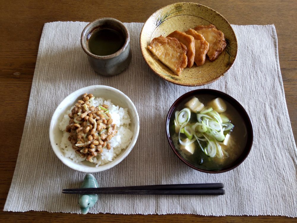 納豆ごはん、黄瀬戸の皿に載った玉ねぎ天、豆腐わかめ麩ねぎの味噌汁。

